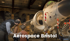 An adult points at a jet plane in a display at the Aerospace Museum in Bristol. The two children with him are looking at the plane.