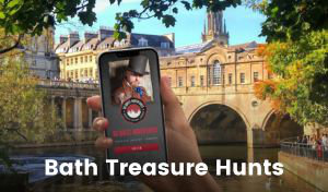 A hand holding a mobile phone that displays the round ‘Go Quest’ logo is overlaid on an image of the Pulteney Bridge in Bath, a historic bridge built from Bath stone with buildings lining its sides