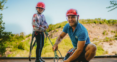 Instructor and girl wearing helmets and harnesses, preparing for Rock Climbing at Mendip Activity Centre—an exciting outdoor activity on a family adventure holiday in Somerset.